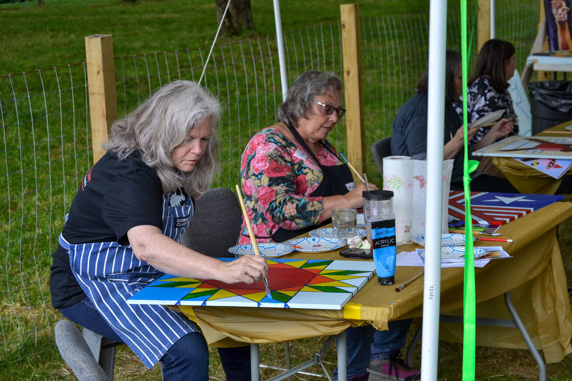 two women painting barn quilt designs